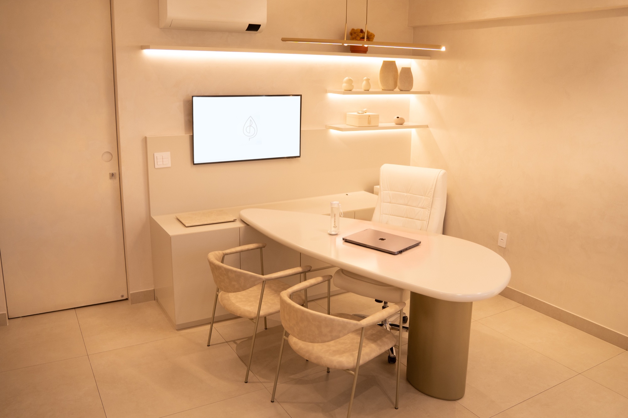 Consultório clean com mesa branca e TV